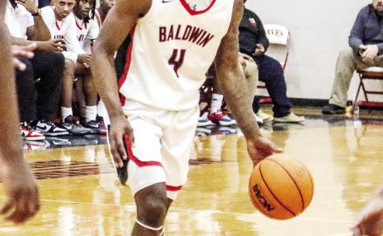 Tre Lawrence dribbles the ball at the top of the key in a game against Swainsboro in February. LANCE MCCURLEY/Staff