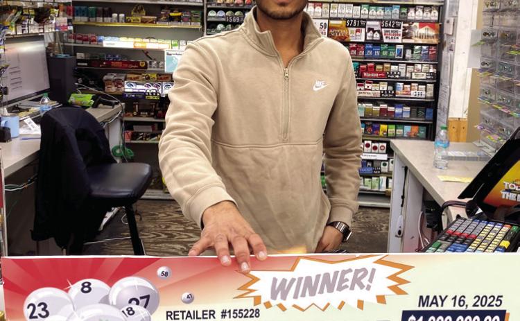 Neel Patel, the co-manager of Texaco Food Mart in Milledgeville, holds up the promotional check, representing the $1 million winning ticket for the Georgia Lottery game 2nd Edition Billionaire Club. Courtesy of Georgia Lottery Corporation