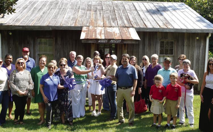 Lockerly Arboretum Executive Director Jennifer Pollard (center, green shirt) and Ellen Patton (center, white dress) cut the ribbon to the renovated Woods Museum with Lockerly Arboretum staff and board members and the Chamber of Commerce. BAILEY BALLARD/Staff