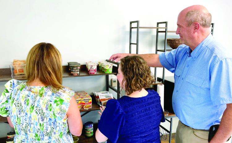 Director of Student Care and Outreach Amy Whatley, Assistant Vice President for Student Health and Wellbeing Emily Jarvis, and Facilities Project Manager Chris Bell stock food during the Campus Corner Open House. COURTESY OF GCSU