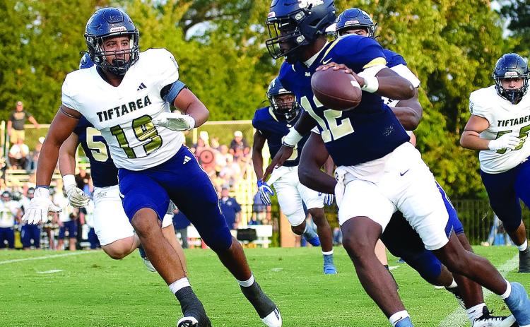 Senior JMA quarterback Lewis Cheney (12) scrambles early in the game last Friday against the visiting Tiftarea Panthers, on his way to leading the Trojans to a dominating 42-7 victory. TREY NORRIS/Staff