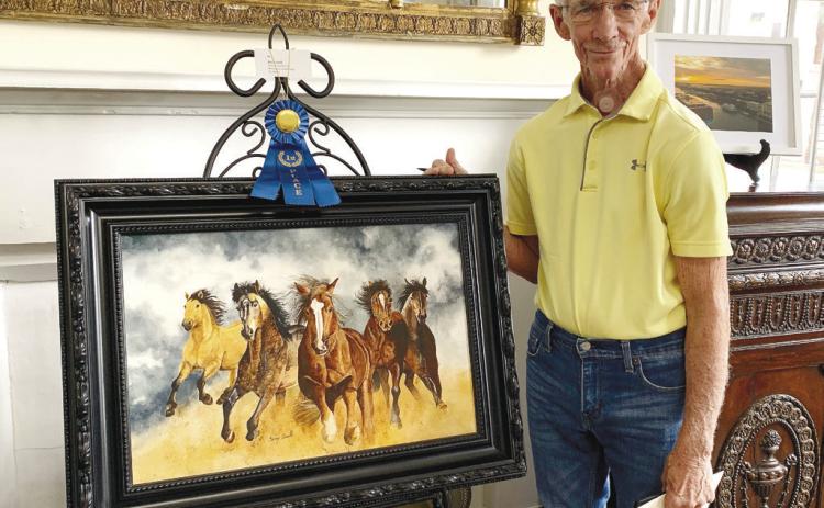 First-place winner Berry Smith stands beside his watercolor piece, “Thundering Hooves.”