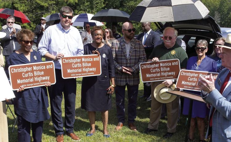 Ocmulgee Judicial Circuit District Attorney T. Wright Barksdale (4th from left, holding sign), Putnam County Sheriff Howard Sills (in green), and State Senator Rick Williams (far right), joined family members of Sgts. Monica and Billue as they received official sign replicas similar to those posted alongside Hwy. 16 in Putnam County. IAN TOCHER/Staff