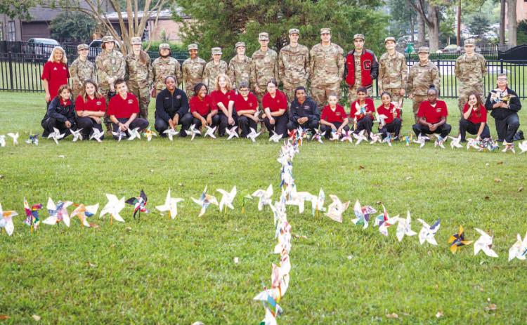 Students gather behind the large peace sign made of their individual pinwheels and celebrate International Peace Day. CONTRIBUTED