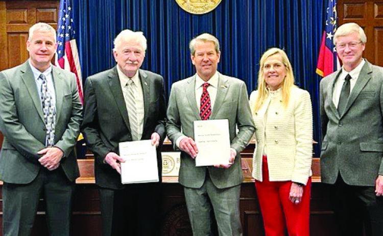ACCG President Henry Craig (left of center) presents the resolutions to Georgia Gov. Brian Kemp (center). CONTRIBUTED