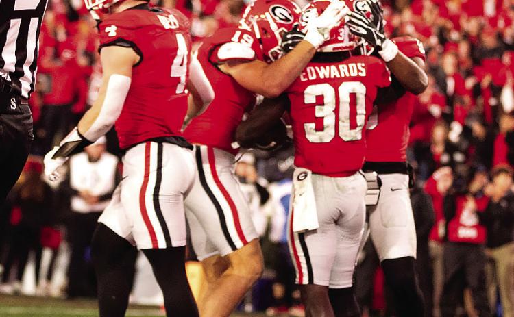 Running back Daijun Edwards (30) is congratulated by teammates after one of his rushing touchdowns. H ZAK ROBINSON PHOTOGRAPHY/Contributed