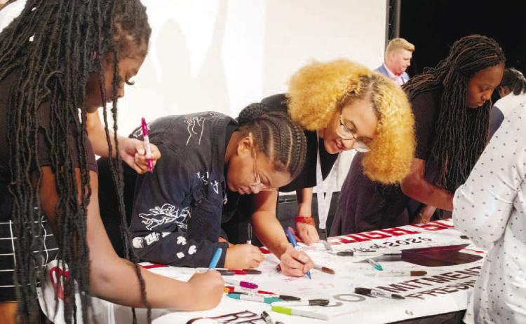 Baldwin High School freshmen students sign a banner with the promise to commit to graduating. ERIC JONES/Contributed
