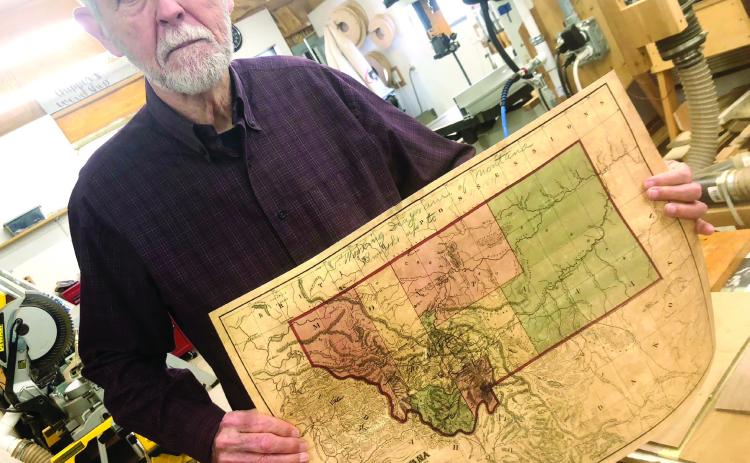 Harold Lawrence shows off one of the maps he uses as part of his research when writing. He refers to maps to ensure historical accuracy. GREENBERRY MOORE/Staff