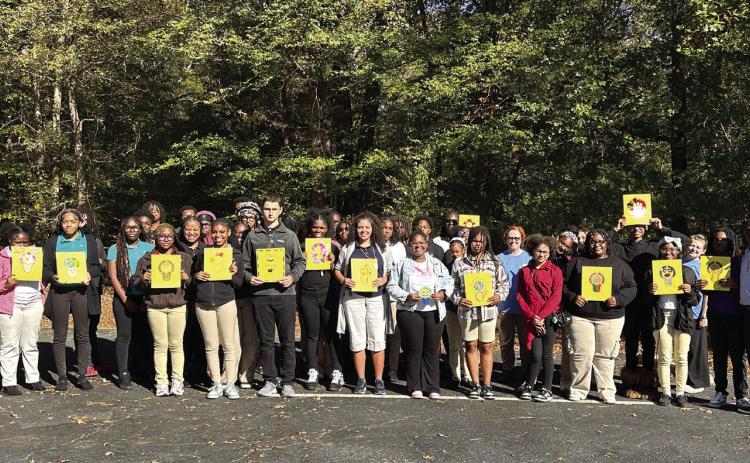 High Achievers hold up their light bulbs representing Lights on Afterschool with group leader Navaeh Jones (far left) and High Achievers Program Coordinator Kennth Daniels (far right). ALIVIA BLANTON/Staff