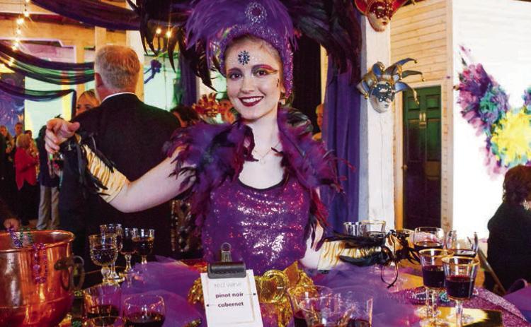 A performer at one of two “living tables” provided wine and ArtiGras beads to guests at The Livery before the party moved next door to Barrel 118.