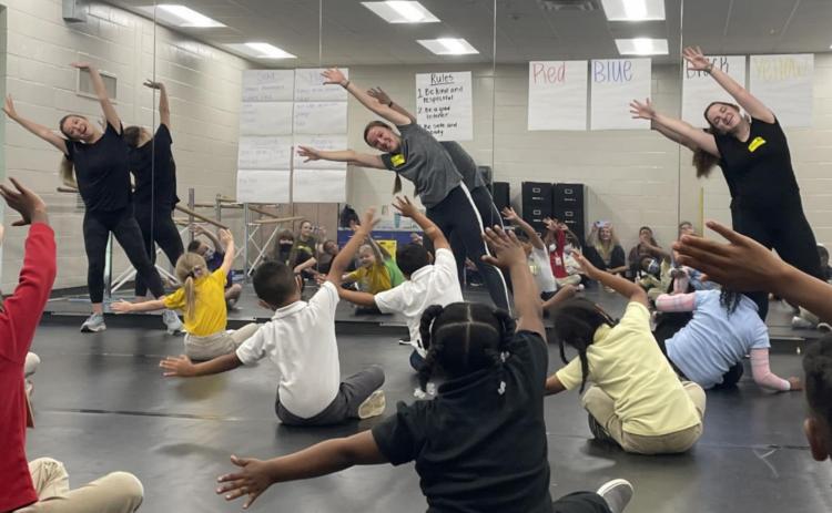 Sophia Sampson, Victoria Grant, and Delaney Faas lead students in stretches. CONTRIBUTED