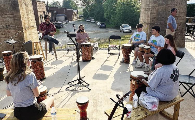 Attendees come together at the center of the Urban Arts Village’s stage for a drum circle. ERIC MOLLENAUER/Staff
