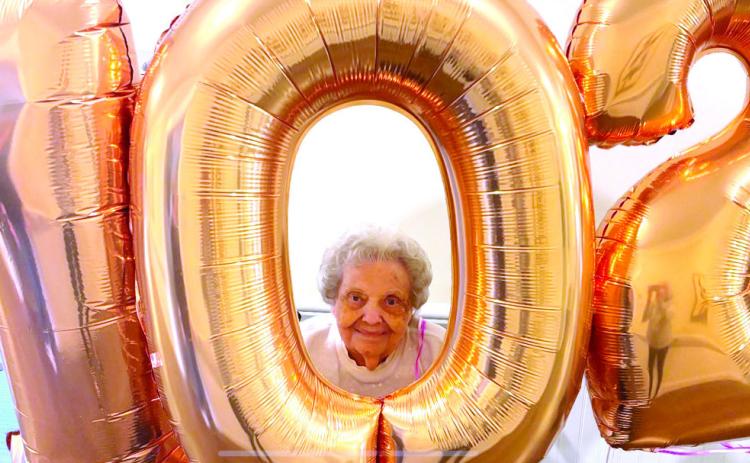 Ginny Cartwright peers out from behind balloons signifying her 102nd birthday, celebrated Dec. 23, at an assisted living facility on Meriwether Road. CONTRIBUTED