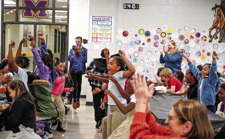 Midway Hills Academy after-school program students cheer at the announcement of achieving their goal. To celebrate their recycling accomplishment students received Battery Hero campaign swag, Chick-fil-A nuggets and cookies, and a visit from the Chick-fil-A cow. ANNA GAY LEAVITT/GCSU