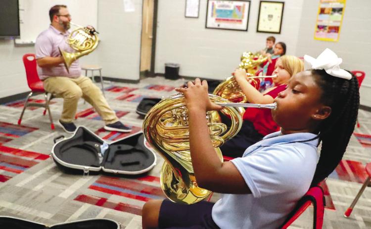Students learn how to hold and play the French horn. ERIC JONES/Contributed