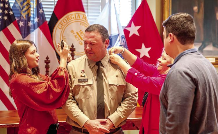 Courson’s daughter Gracie (left), son Landon (front) and wife, Kim (right) change his epaulets from major to lieutenant colonel. COURTESY OF GMC