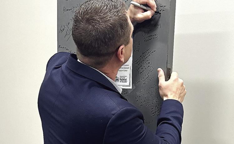Baldwin County Board of Commissioners Chairman Andrew Strickland signs the door commemorating President Jimmy Carter’s contributions to Habitat for Humanity. CONTRIBUTED