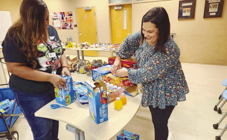 Midway Hills Primary Counselor Sonya Murray and EIP Teacher Anna Dunn prepare the juice boxes for the food packages of approximately 40 families in Baldwin County during winter break in December. CONTRIBUTED