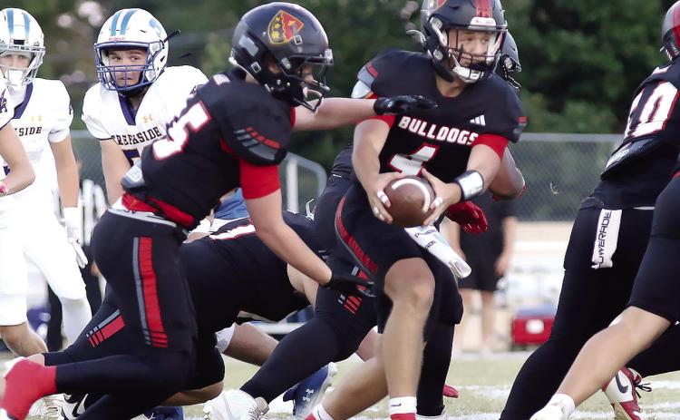 John Milledge Academy quarterback Cason Dennis (center) hands off the ball to junior fullback Evan Stasney, who racked up 171 yards rushing while scoring two touchdowns in the Trojans’ 45-14 win last Friday over Creekside Christian Academy. TREY NORRIS/Staff