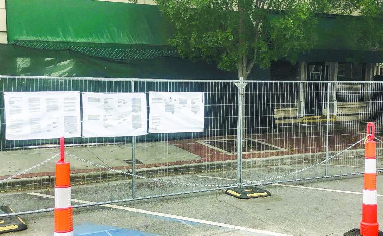 Passers-by can read documents filed with the petition that have been attached to fencing put up by the city as a safety precaution in front of 107 and 115 S. Wayne St. GREENBERRY MOORE/Staff