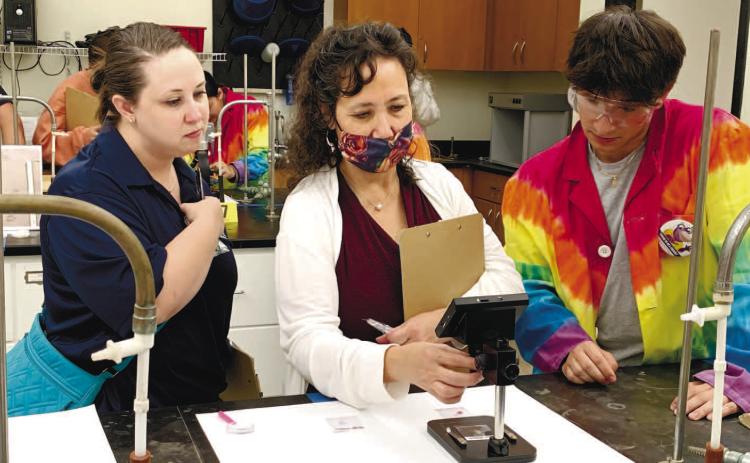 Two investigators and a lab assistant compare hair samples to the offender’s hair sample.