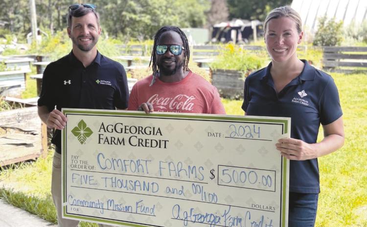 Executive Director of Comfort Farms Jon Jackson (center)accepts a $5,000 donation to fund the new herb garden initiative. CONTRIBUTED