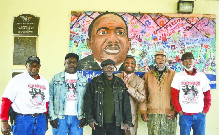 Members of the Southern Christian Leadership Conference pose in front of a Martin Luther King Jr. memorial.