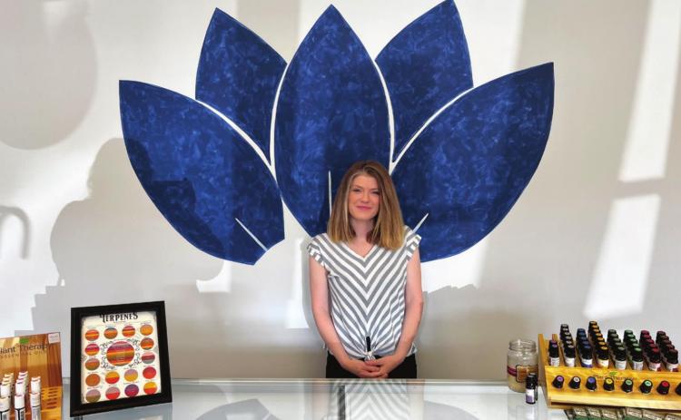Leslie Rawlins, the owner of Central Harvest in Gray, poses for a photo in front of the mural inside her business.