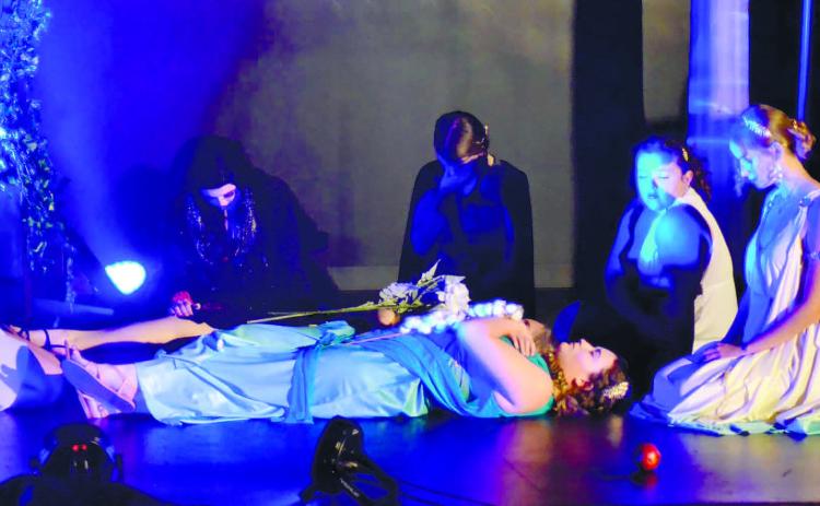 The goddesses kneel with heads bowed as they look upon Persephone’s body with grief. CONTRIBUTED