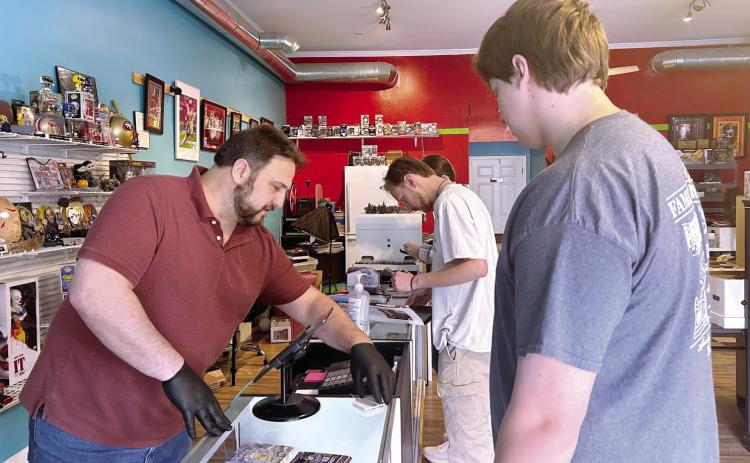 Hill speaks with a customer in his store The Ript Zone. Alongside cards and collectibles, it sells memorabilia for many movies, including Star Wars. ANNA HOLLIS/Staff