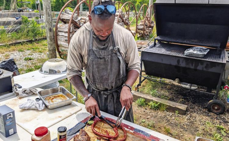Jon Jackson works the grill during the farmer’s market. ANDREW BROWN/Staff