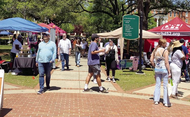 Locals walk through vendor tables on Georgia College &amp; State University’s front campus, where the festival took place. GRACIE HOWARD/Staff