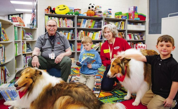 Students read to collies, Skye and Laddie, in the school library once a week, guided by their owners Jay and Susan Wucher. CONTRIBUTED