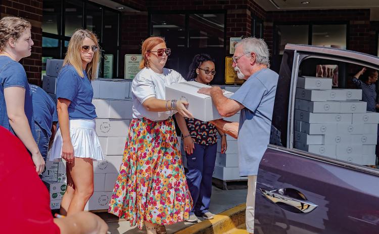 Volunteers of the Summer Meals Program help load cars at distribution sites to send home fresh food for families in need. CONTRIBUTED