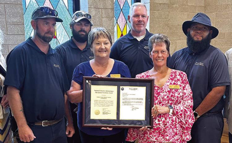 Director James Earp (far right) of the Veterans Affair’s National Cemetery Administration Grants Program presents Director Linda Lavender (blue shirt) of Milledgeville’s Georgia Veterans Memorial Cemetery and its grounds crew with the National Cemetery Administration Operational Excellence Award. HUDSON TAYLOR/Staff