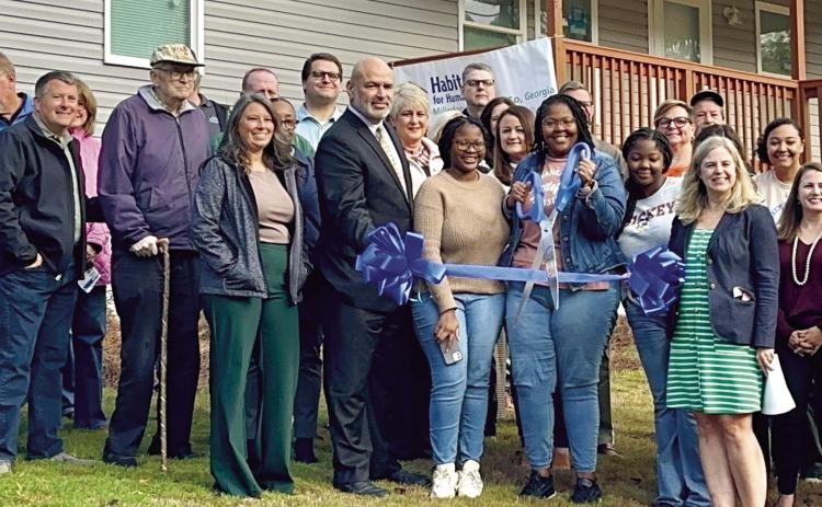 Vodiksha Coffee (center) cuts the ribbon to her family’s brand new home. ALIVIA BLANTON/Staff