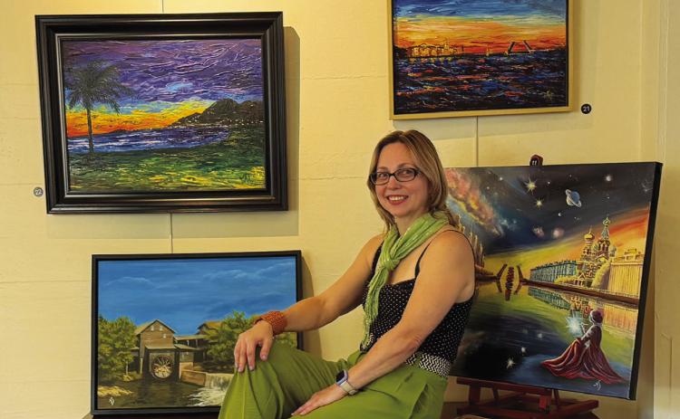 Victoria Anadenko is pictured among works from her exhibit at Allied Arts. The nearly 40-piece collection includes landscapes, architecture, animals and imaginative compositions in a variety of media and styles.